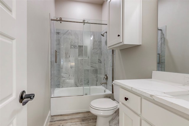 full bathroom with toilet, bath / shower combo with glass door, wood finished floors, and vanity