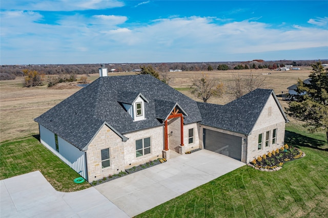 view of front of property with an attached garage, a shingled roof, driveway, stone siding, and a front yard