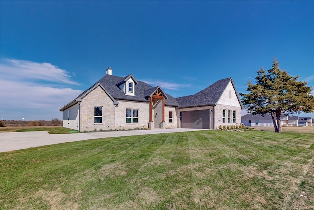 view of front facade with driveway, stone siding, a chimney, an attached garage, and a front lawn