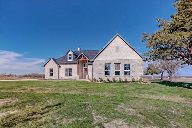 french country inspired facade with stone siding, brick siding, a chimney, and a front yard