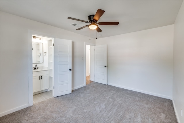 unfurnished bedroom with light carpet, ensuite bathroom, sink, and ceiling fan