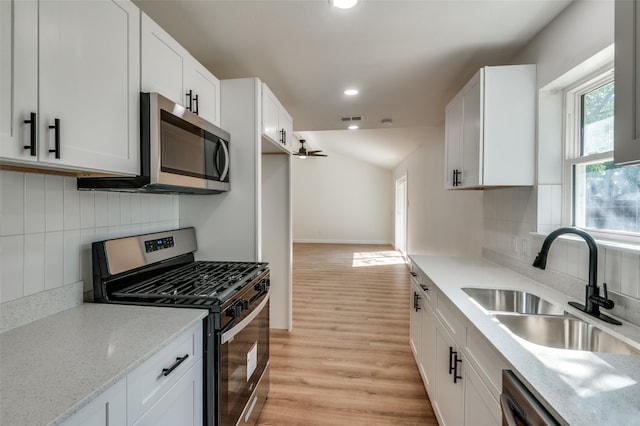 kitchen with white cabinets, stainless steel appliances, light wood-type flooring, and backsplash