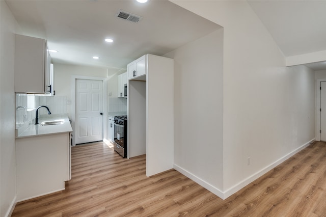 kitchen with sink, white cabinetry, decorative backsplash, and light wood-type flooring