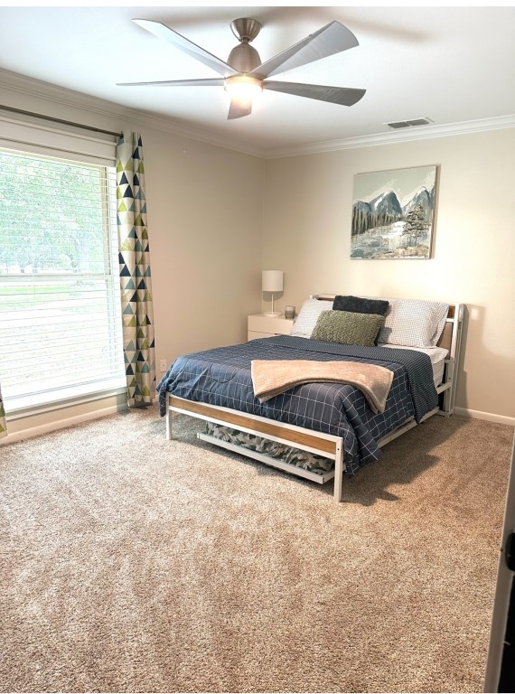 bedroom with ceiling fan, crown molding, and carpet