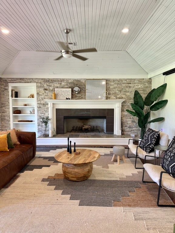 carpeted living room with lofted ceiling, a tiled fireplace, wooden ceiling, and built in shelves