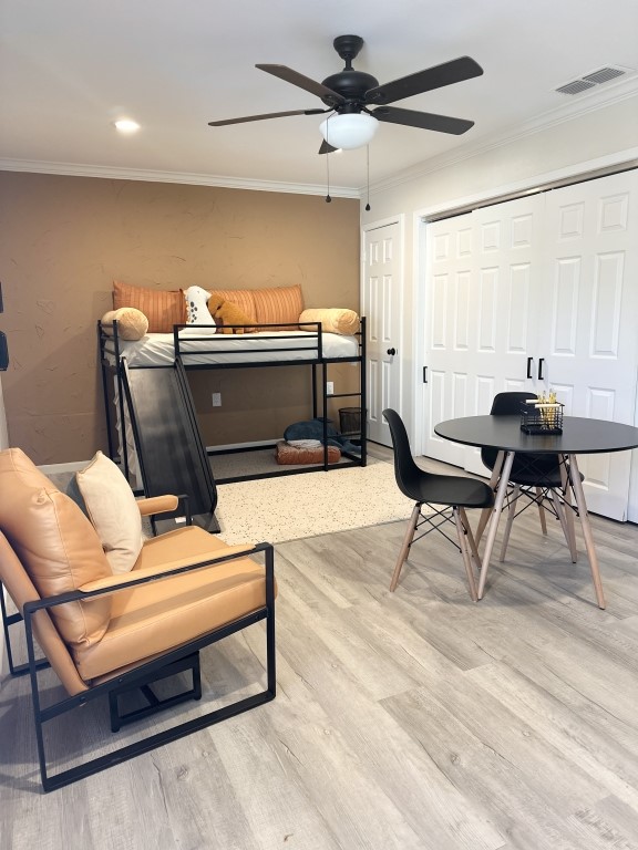 bedroom featuring crown molding, light wood-type flooring, and ceiling fan