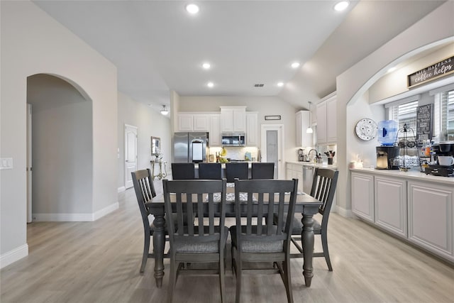 dining space with light wood-type flooring and vaulted ceiling