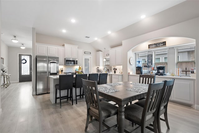 dining area featuring vaulted ceiling and light wood-type flooring