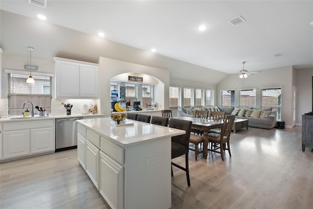 kitchen with plenty of natural light, a center island, stainless steel dishwasher, and white cabinets