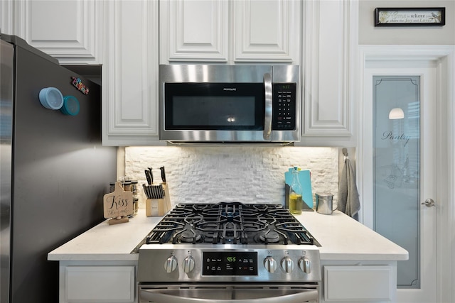 kitchen with tasteful backsplash, appliances with stainless steel finishes, and white cabinets