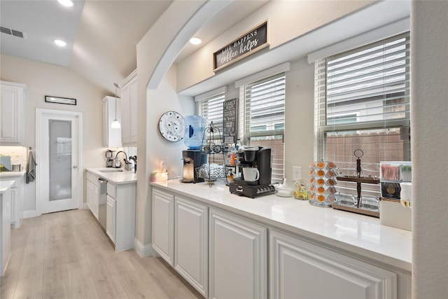 bar featuring dishwasher, light hardwood / wood-style flooring, sink, vaulted ceiling, and white cabinetry