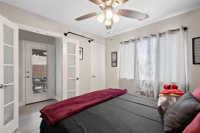 bedroom with light hardwood / wood-style flooring, access to exterior, a barn door, and ceiling fan