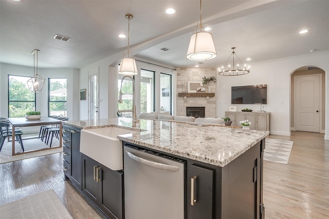 kitchen featuring dishwasher, decorative light fixtures, and a center island with sink