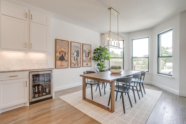 dining space featuring light hardwood / wood-style floors, wine cooler, a chandelier, and bar area