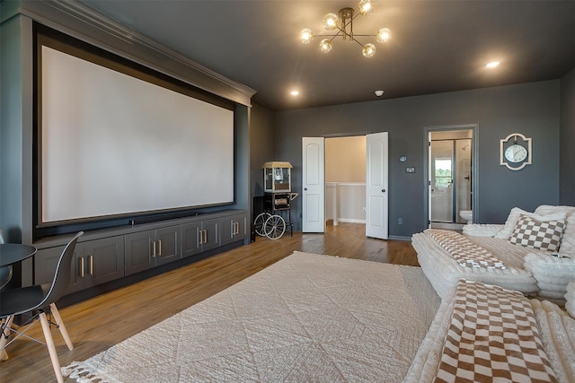 cinema room with ornamental molding, hardwood / wood-style floors, and an inviting chandelier