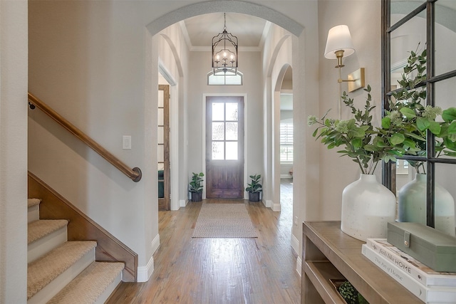 foyer with ornamental molding, light hardwood / wood-style flooring, and an inviting chandelier