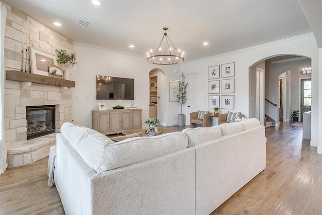 living room with light hardwood / wood-style floors, crown molding, and a fireplace