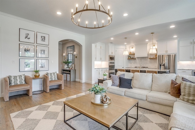 living room with ornamental molding, sink, and light wood-type flooring