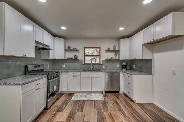 kitchen with white cabinetry, sink, appliances with stainless steel finishes, light stone countertops, and dark hardwood / wood-style flooring