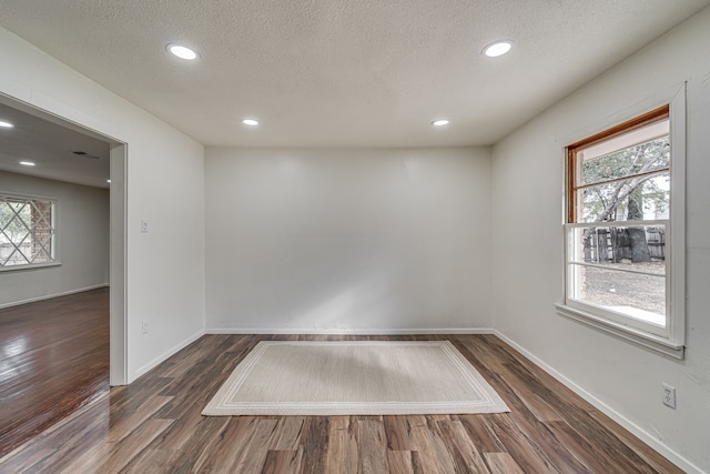 unfurnished room featuring dark hardwood / wood-style flooring, a textured ceiling, and plenty of natural light