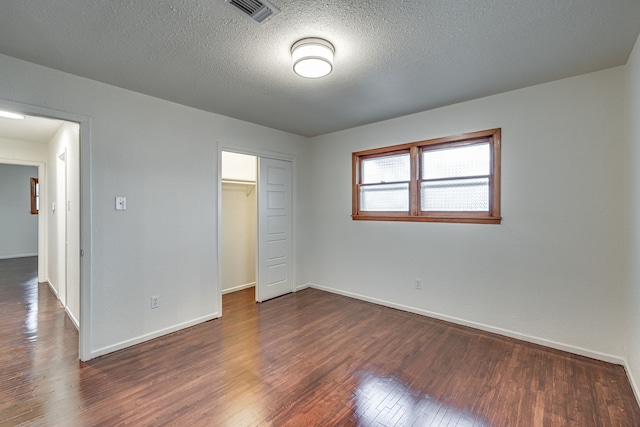 unfurnished bedroom featuring dark wood-type flooring, a textured ceiling, and a closet