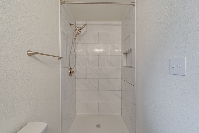 bathroom with toilet and a tile shower