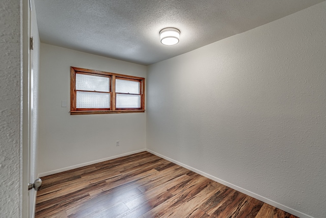 spare room with dark wood-type flooring and a textured ceiling