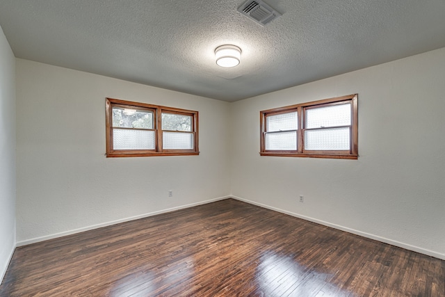 unfurnished room with a textured ceiling and dark hardwood / wood-style floors