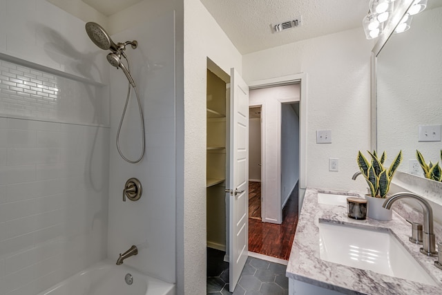 bathroom featuring hardwood / wood-style floors, vanity, a textured ceiling, and bathing tub / shower combination