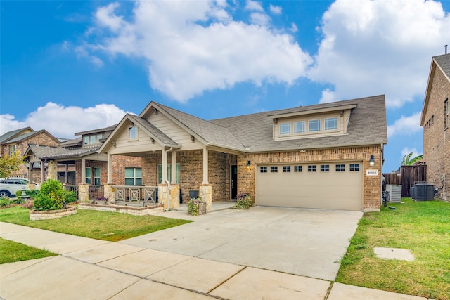 craftsman-style home with central air condition unit, a front yard, a porch, and a garage