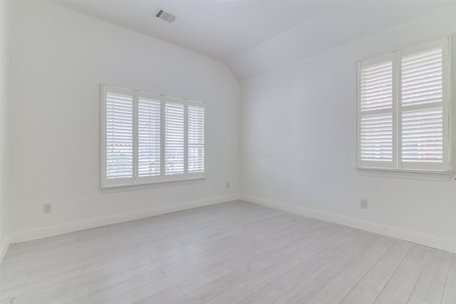 unfurnished room featuring a wealth of natural light, vaulted ceiling, and light wood-type flooring