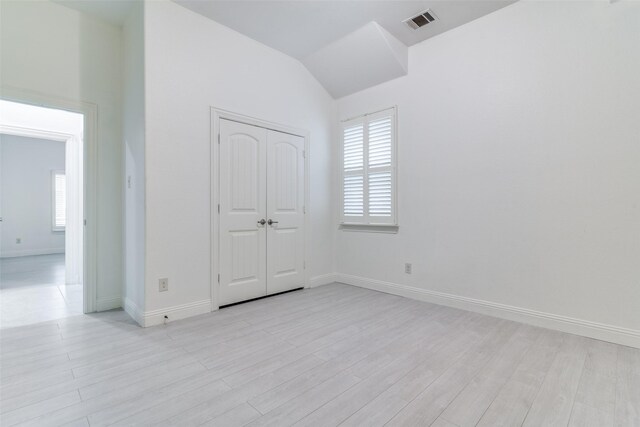 unfurnished room with healthy amount of natural light, baseboards, light wood-style flooring, and lofted ceiling