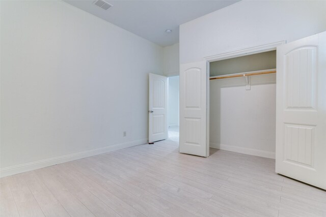 unfurnished bedroom with light wood finished floors, a closet, and baseboards