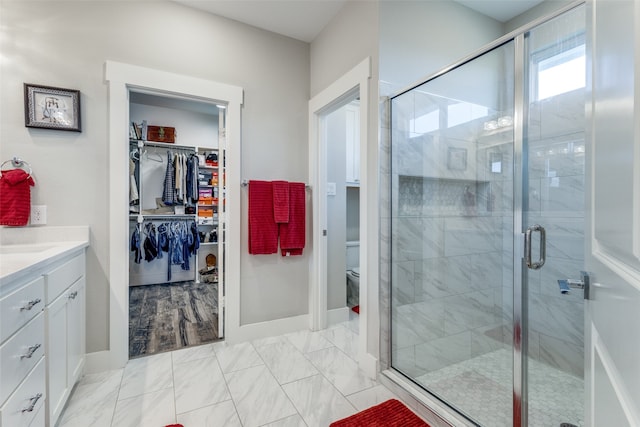 bathroom with vanity, toilet, and a shower with door