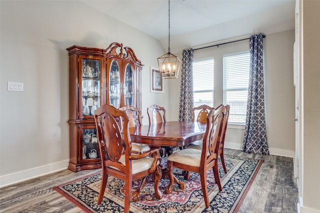 dining space featuring hardwood / wood-style floors, vaulted ceiling, and a chandelier