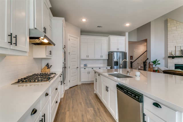 kitchen with appliances with stainless steel finishes, light hardwood / wood-style flooring, white cabinets, and sink