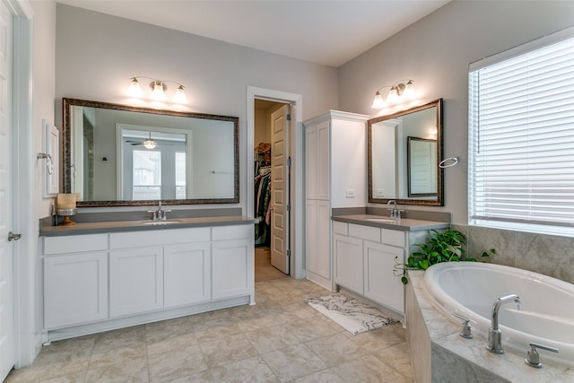 bathroom featuring vanity, tile patterned flooring, a relaxing tiled tub, and ceiling fan