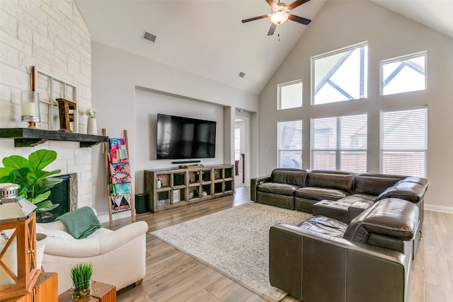 living room with light hardwood / wood-style floors, high vaulted ceiling, a wealth of natural light, and a fireplace