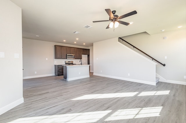 unfurnished living room featuring ceiling fan, sink, and light wood-type flooring