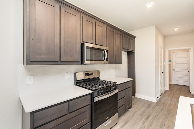 kitchen featuring stainless steel appliances, dark brown cabinets, light wood-type flooring, and decorative backsplash