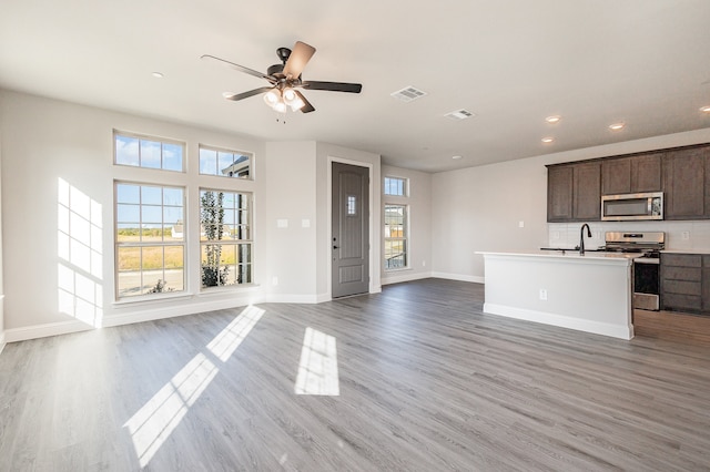 kitchen featuring dark brown cabinetry, a kitchen island with sink, stainless steel appliances, and wood-type flooring