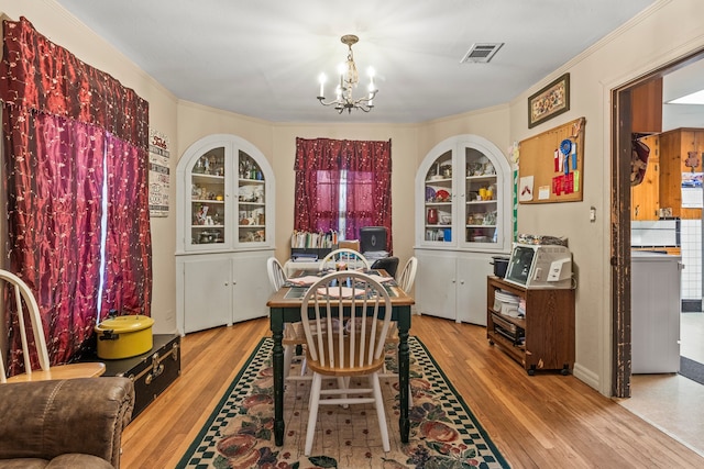 dining space featuring crown molding, a notable chandelier, and light hardwood / wood-style flooring