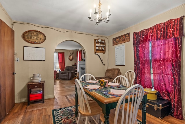 dining area with light hardwood / wood-style floors, a notable chandelier, and crown molding