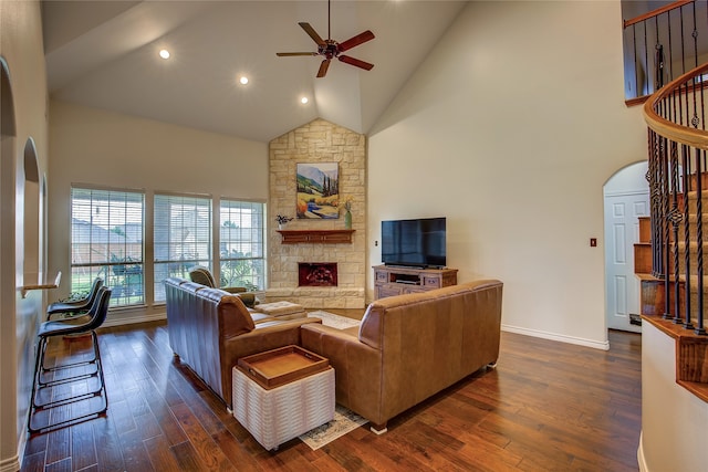 living room featuring a stone fireplace, high vaulted ceiling, dark wood-type flooring, and ceiling fan