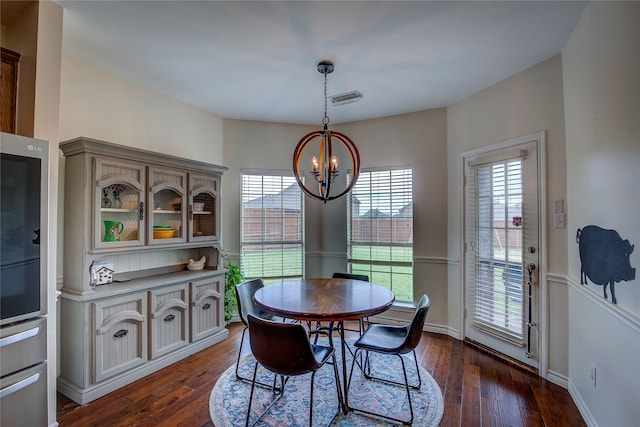 dining area featuring dark wood-type flooring and an inviting chandelier