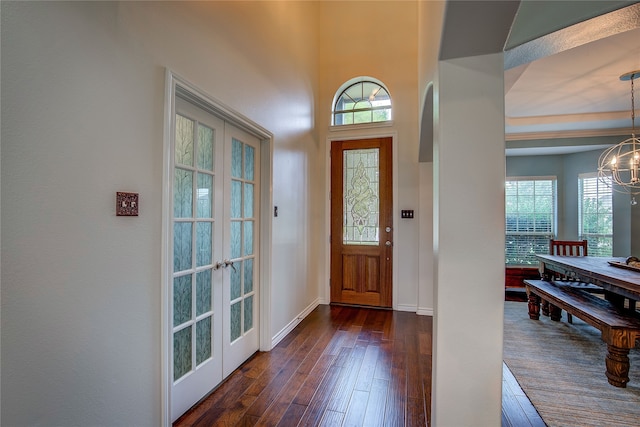 entrance foyer featuring dark wood-type flooring, a notable chandelier, and french doors