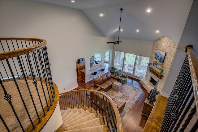 living room featuring ceiling fan, a stone fireplace, high vaulted ceiling, and dark hardwood / wood-style flooring