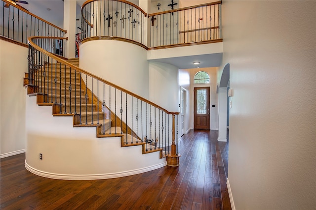 entrance foyer featuring a towering ceiling and wood-type flooring