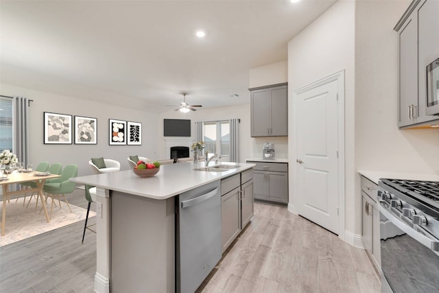 kitchen with an island with sink, light hardwood / wood-style flooring, stainless steel appliances, sink, and a kitchen bar