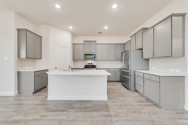 kitchen with light hardwood / wood-style flooring, stainless steel appliances, and gray cabinetry